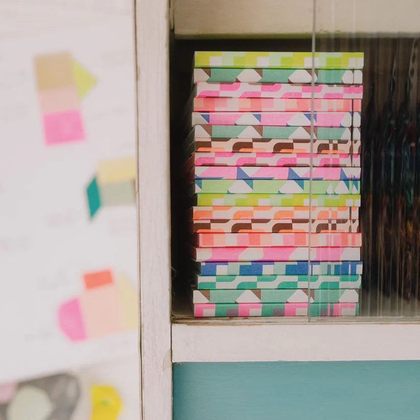 Stack of colorful patterned notebooks inside a cabinet.