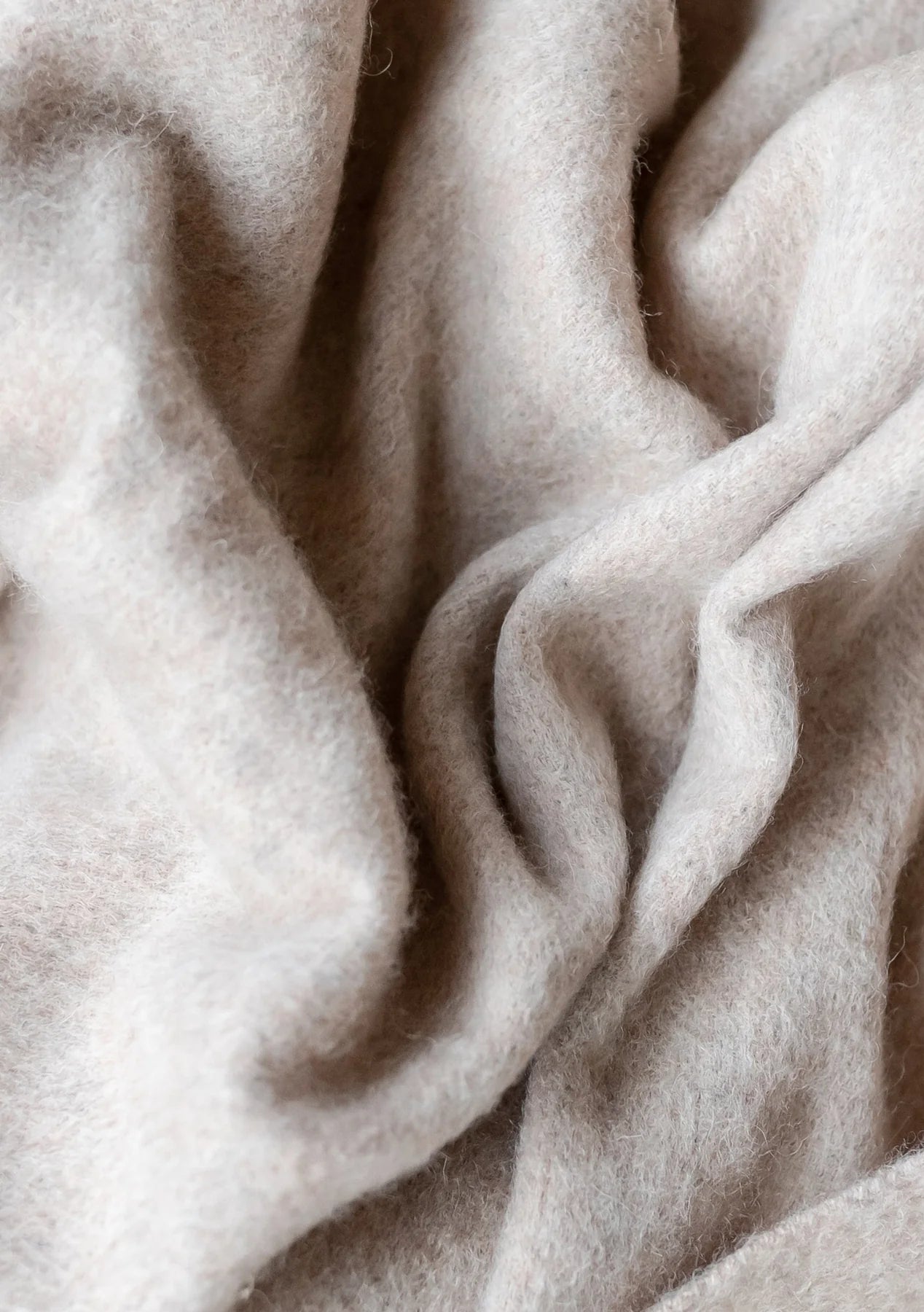 Soft, light beige fabric with a fluffy texture, draped in folds and wrinkles.