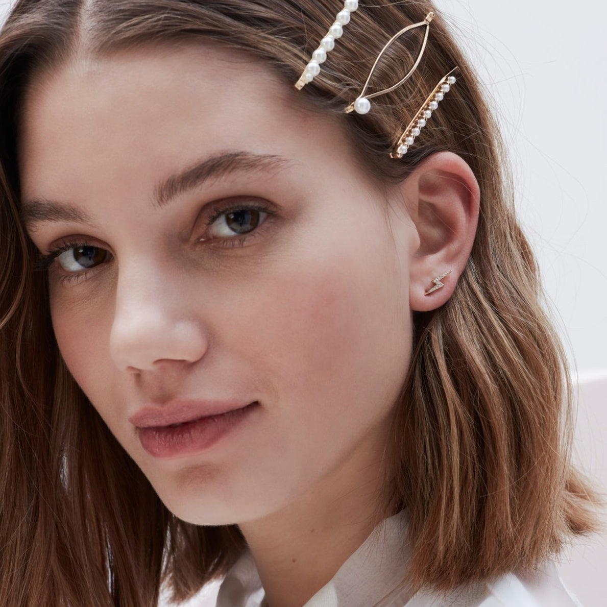 Gold hair clips adorned with pearls and a pair of lightning bolt earrings.