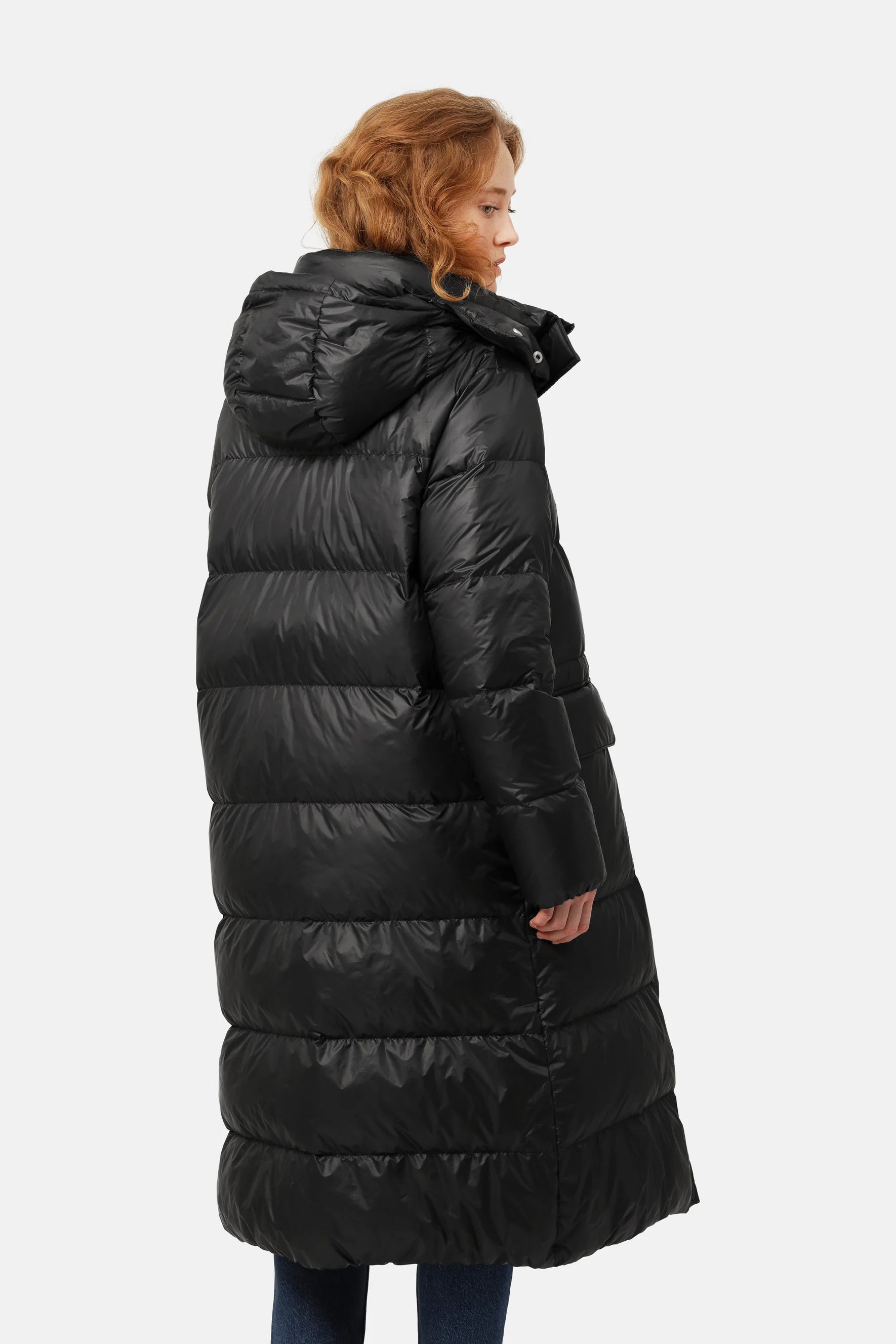 Black long puffer coat with a hood, shown from the back on a model. Shiny, quilted texture.