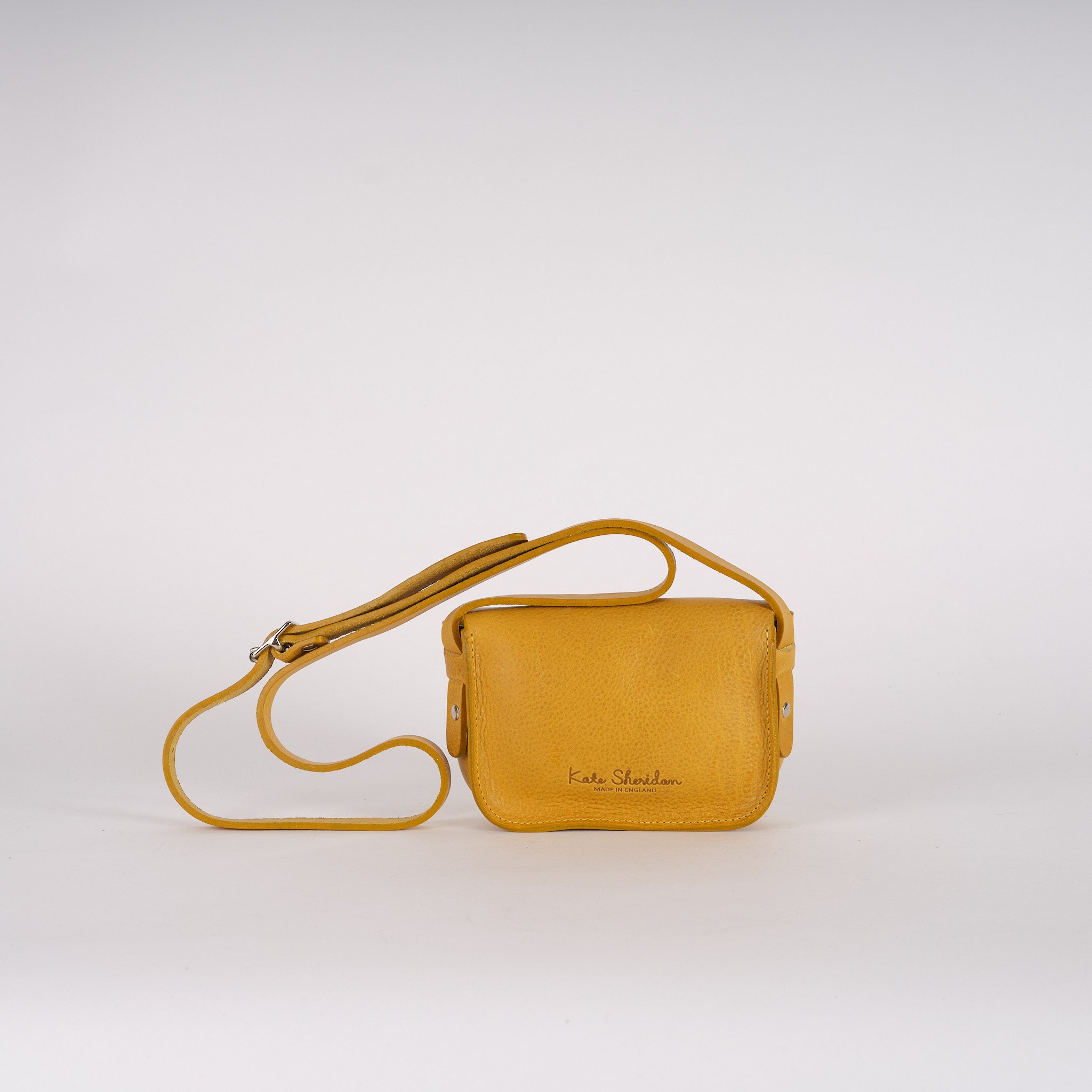 Mustard yellow leather crossbody bag with adjustable strap.  "Kate Sheridan, Made in England" is subtly embossed on the bag.