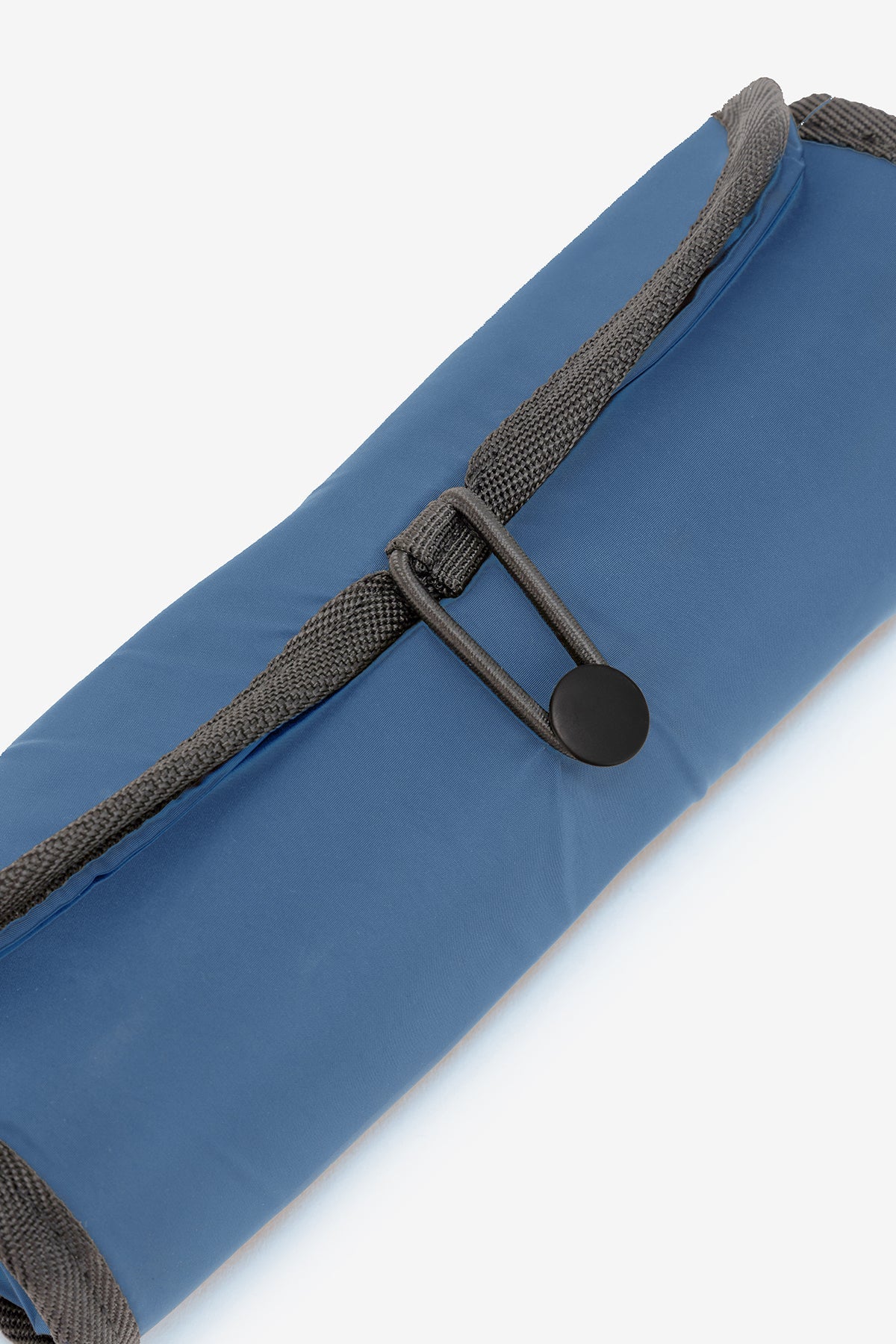 Rolled blue fabric shopping bag with gray straps and a black button closure.