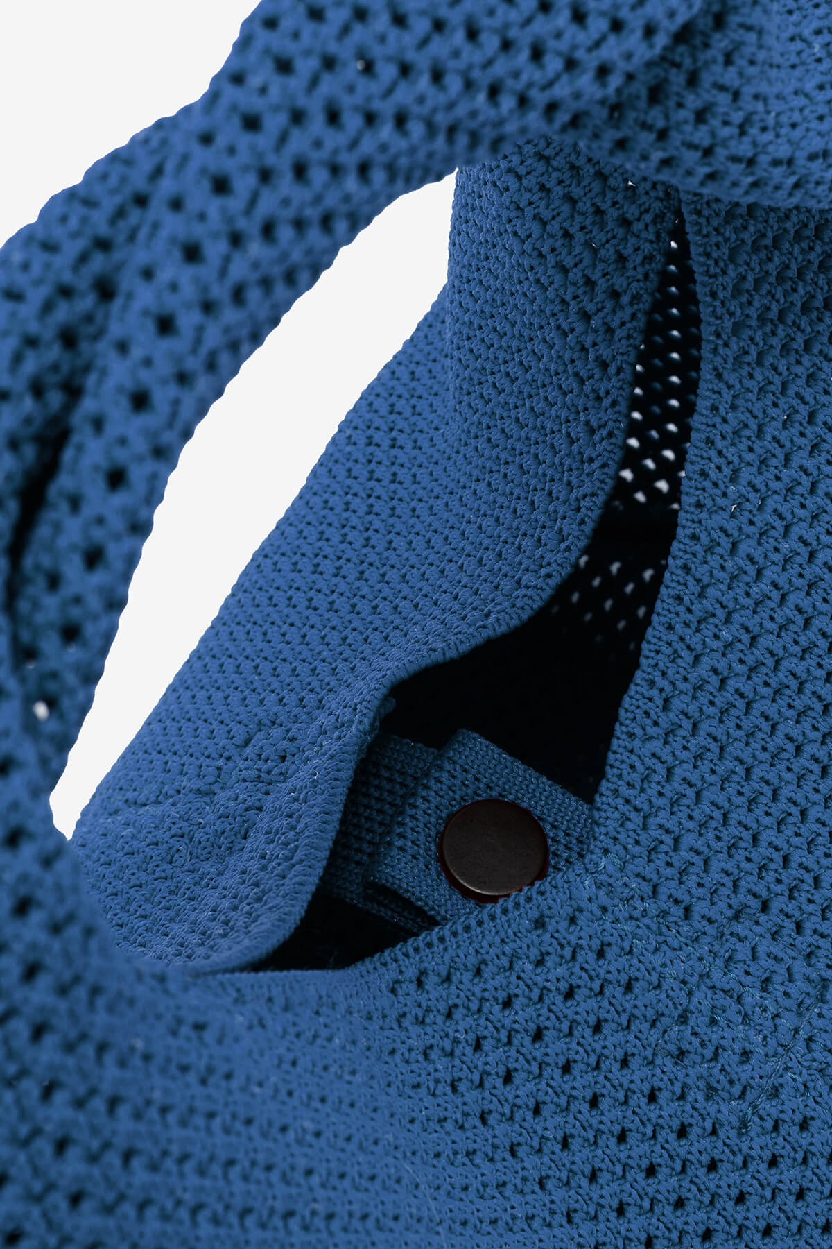 Close-up of a blue crocheted handbag with a visible clasp. The bag's texture is detailed, showing an open-weave pattern.