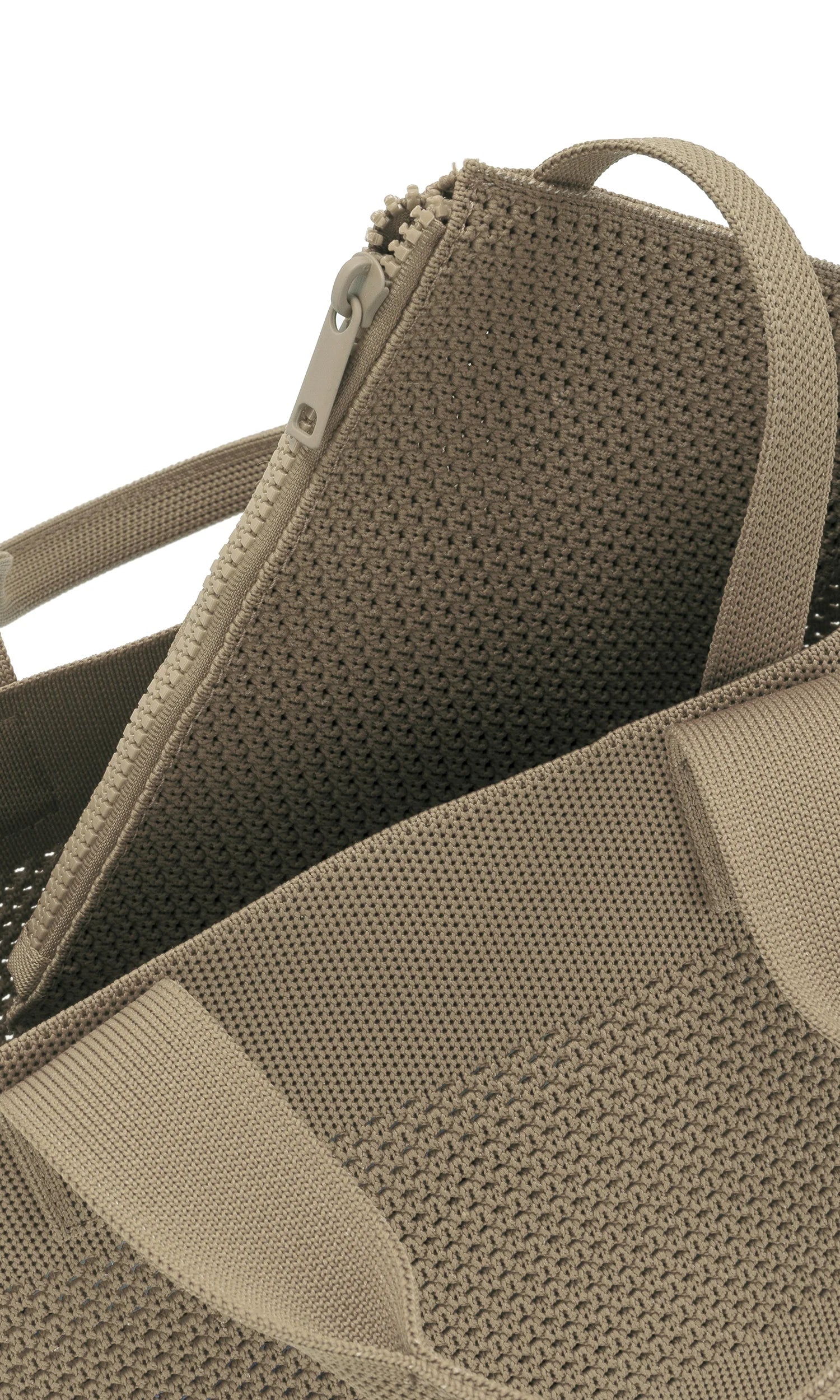 Beige knitted tote bag with zipper closure and top handles. The fabric has an open, textured weave.