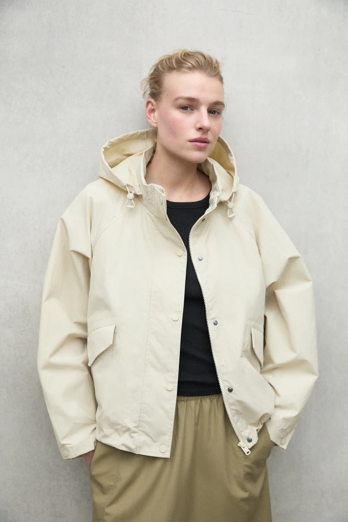 Cream-colored hooded jacket with snap closures and pockets.