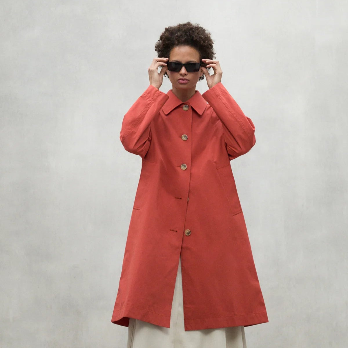 A terracotta-colored, button-front, knee-length coat.