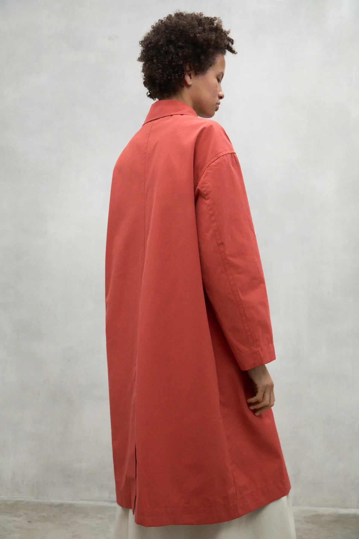 Coral-colored long coat with a collared neckline and three-quarter sleeves.