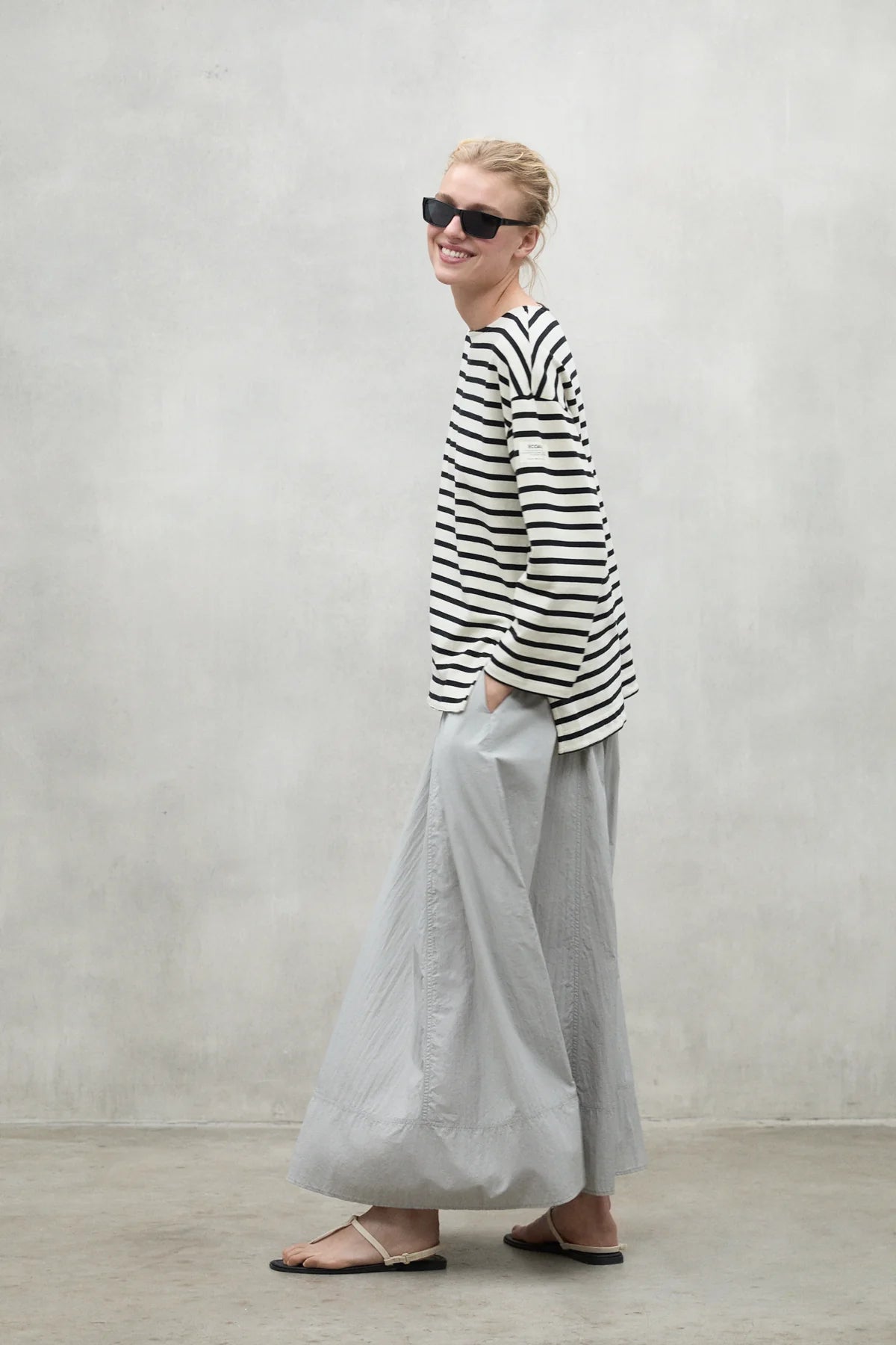 Woman wearing a black and white striped long-sleeve shirt and light gray wide-leg pants.