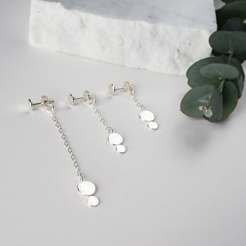 Three pairs of silver dangle earrings. Each earring features a small post and a delicate chain with two textured disc charms.