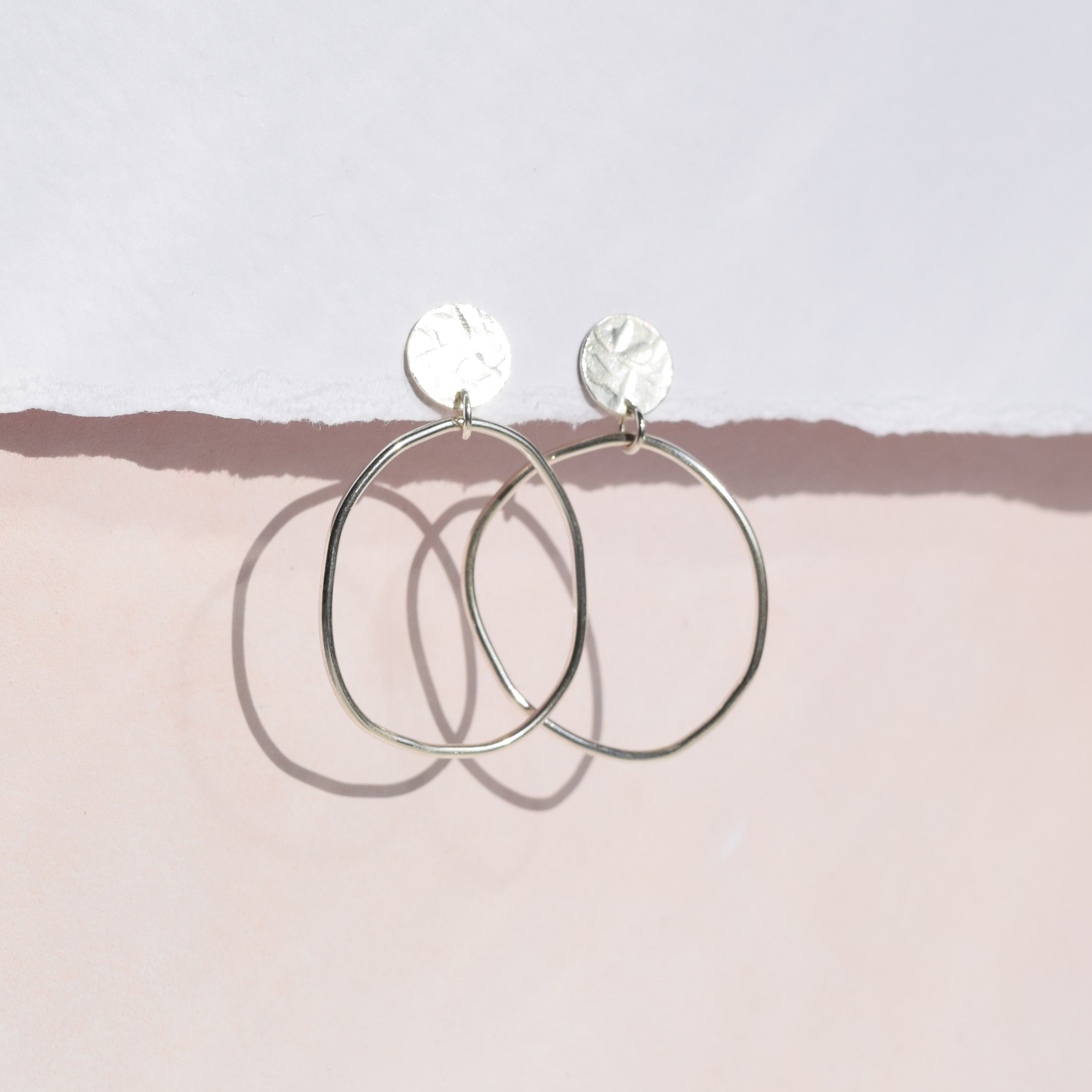 Silver hoop earrings with textured circular accents.