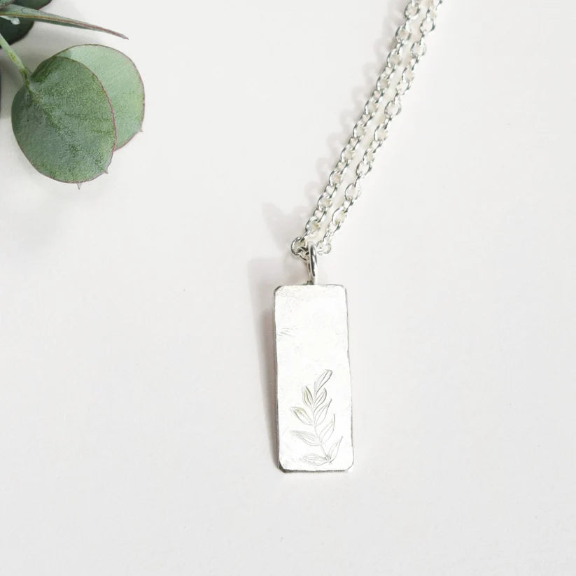 Silver necklace with a rectangular pendant featuring an etched sprig design.