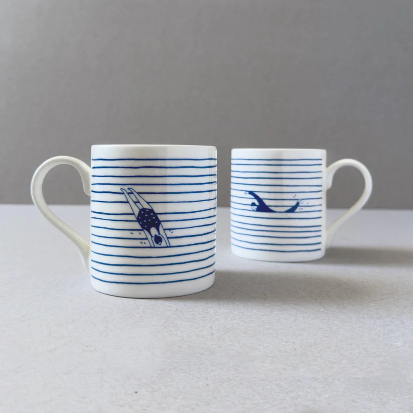 Two white mugs with blue horizontal stripes; each mug features a simple illustration of a swimmer diving underwater.