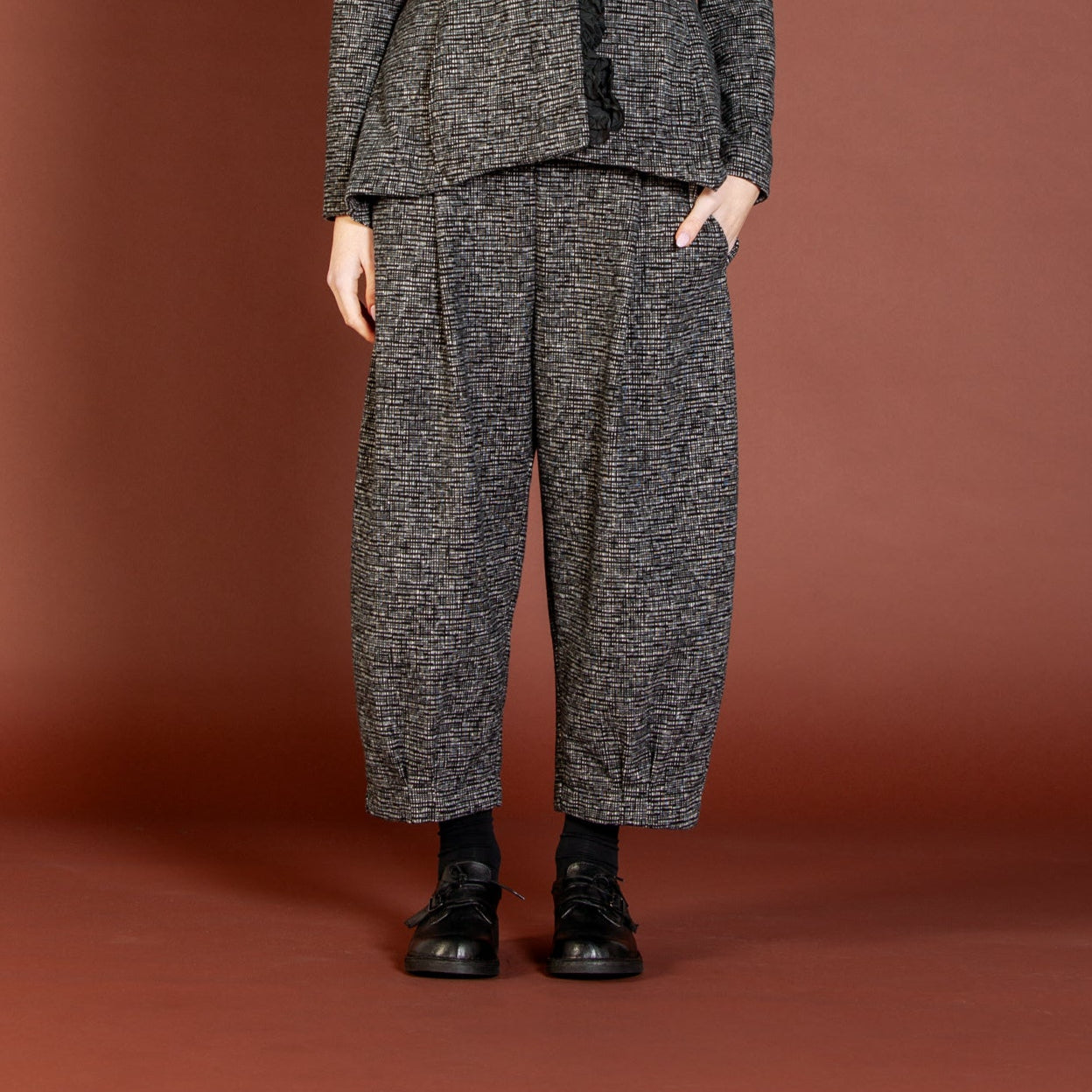 Woman wearing a gray textured suit against a brown background