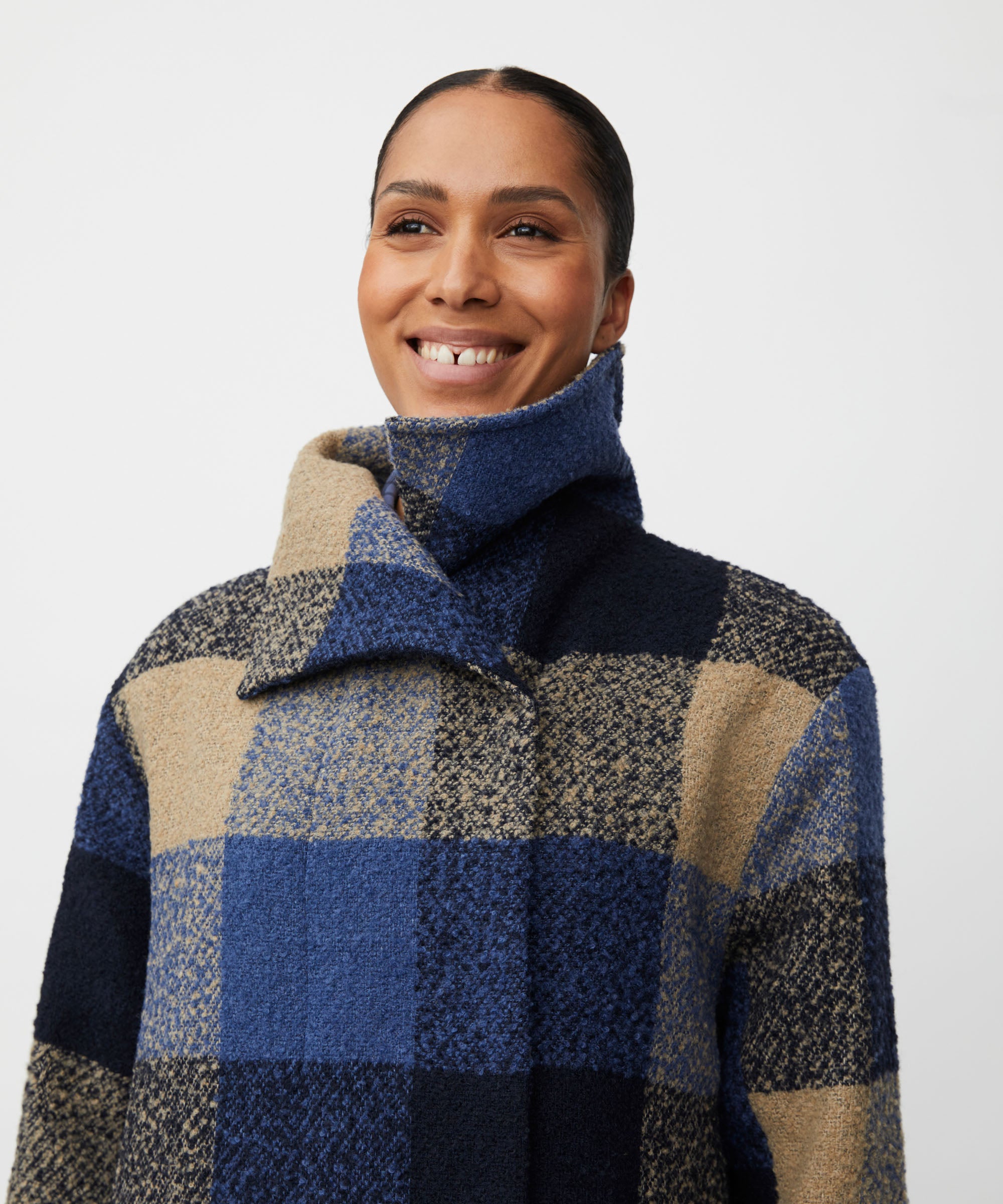 Person wearing a checkered coat with blue and beige patterns on a white background