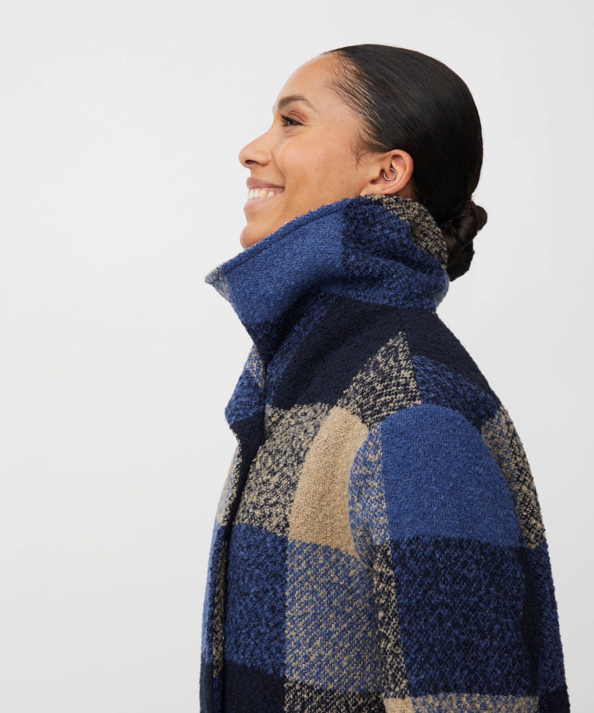 Woman wearing a blue and beige checkered coat on a white background