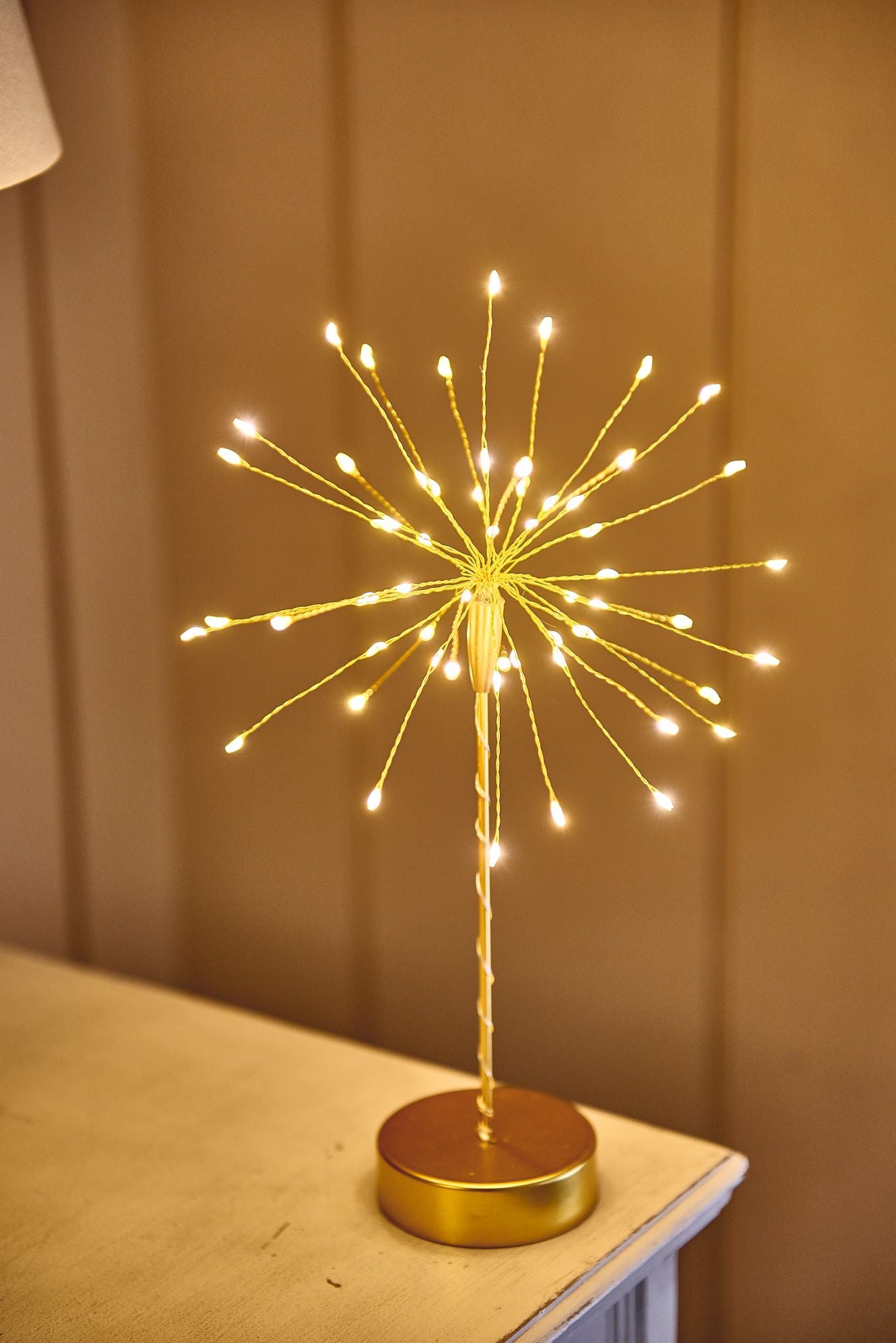 Gold metal tabletop firework light with numerous small warm-white LED lights.