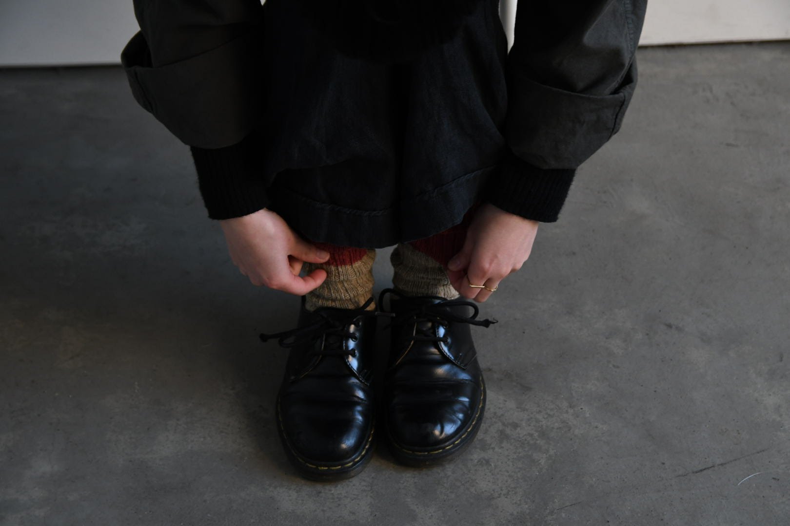 Pair of black leather Dr. Martens shoes with striped socks.