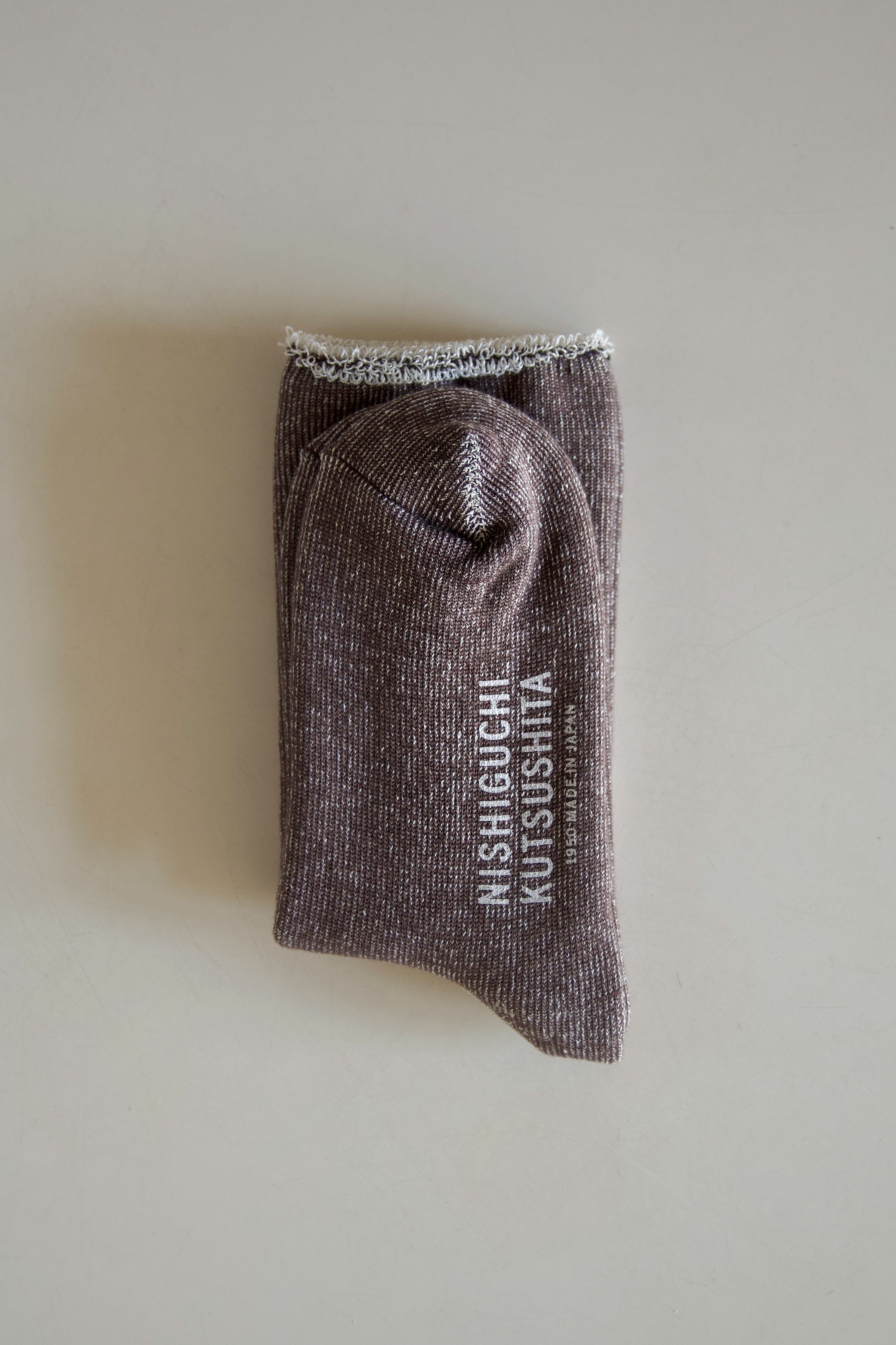 Brown ribbed socks folded, featuring "NISHIGUCHI KUTSUSHITA 1950 MADE IN JAPAN" branding.