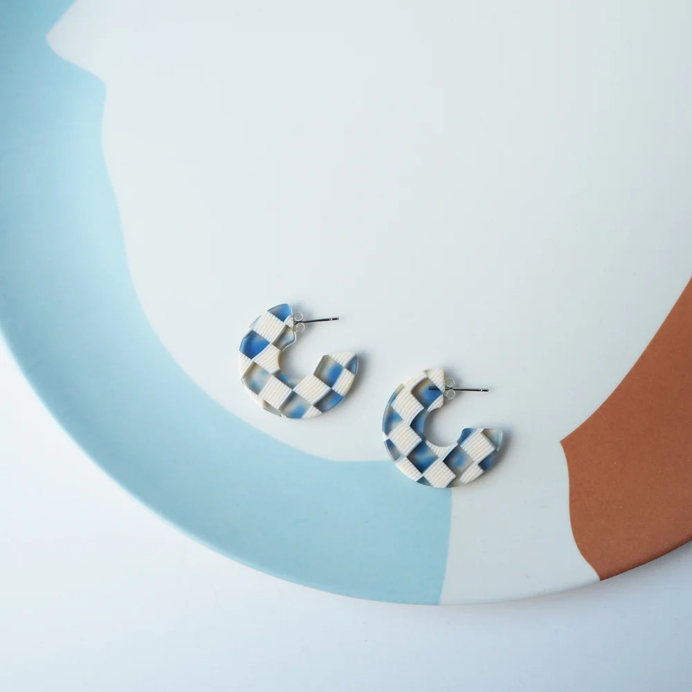 Pair of blue and white checkered resin hoop earrings.