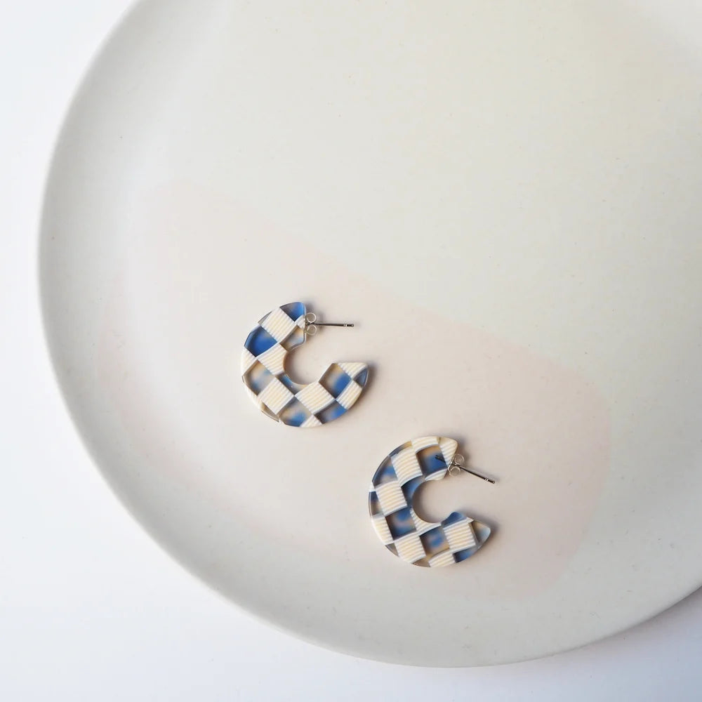 Pair of cream and blue checkered resin hoop earrings.
