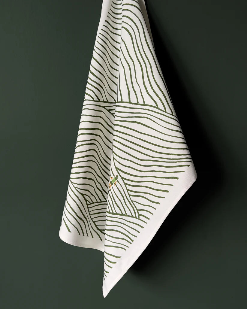 White tea towel with a green abstract landscape design featuring thin, wavy lines.
