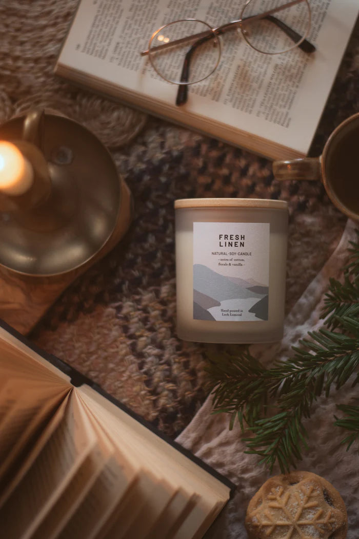 Fresh Linen soy candle in frosted glass jar with wooden lid; label depicts landscape.