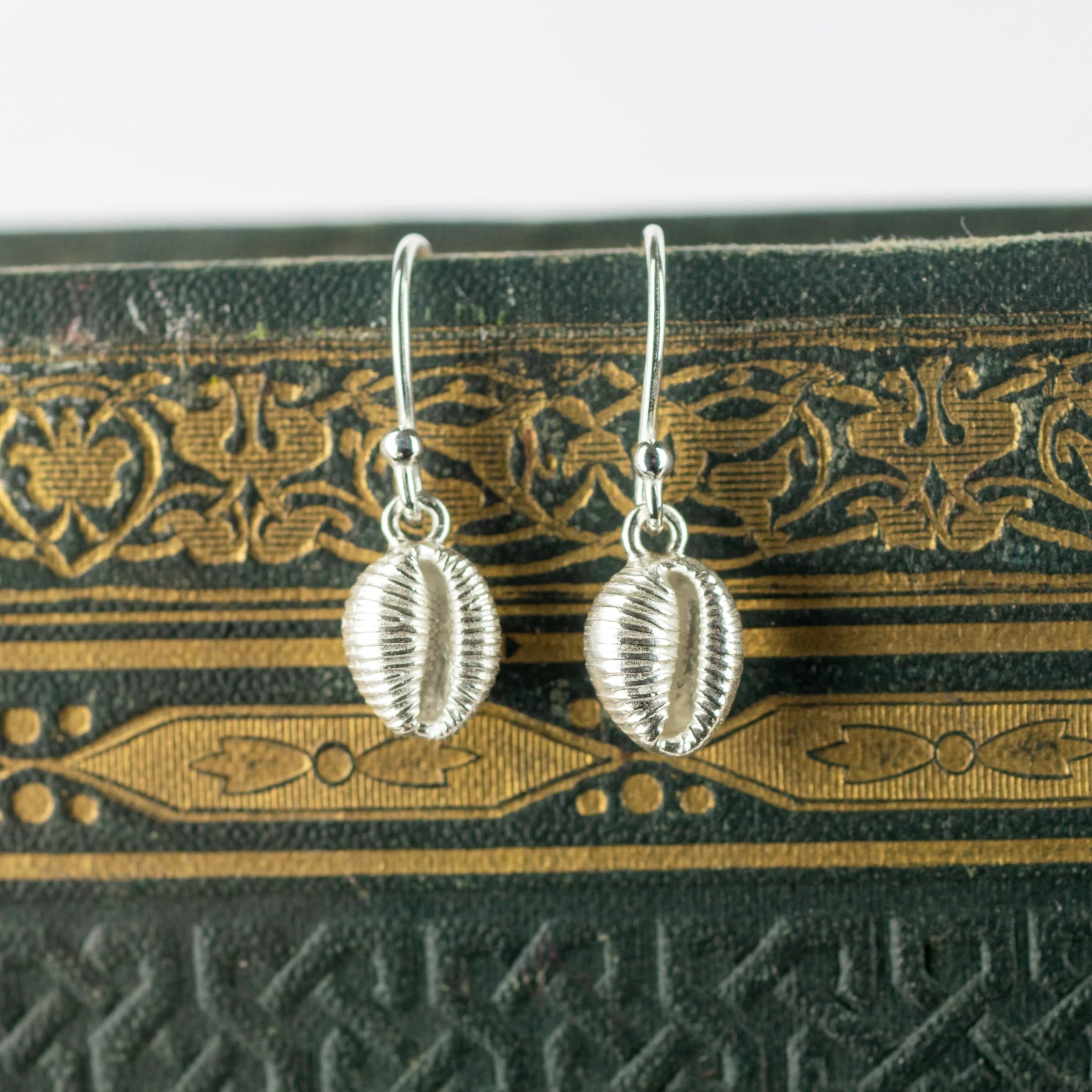 Pair of silver shell-shaped drop earrings with textured surfaces and delicate wire hooks.