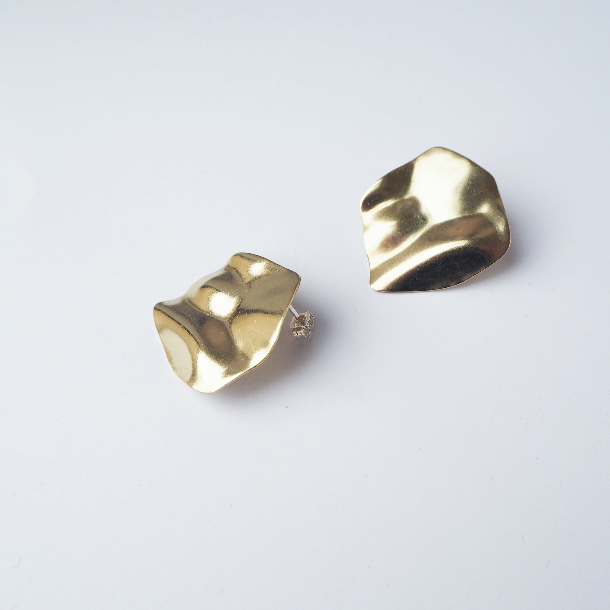 Pair of gold, textured, irregular-shaped earrings.  The earrings have a slightly wavy, organic appearance.