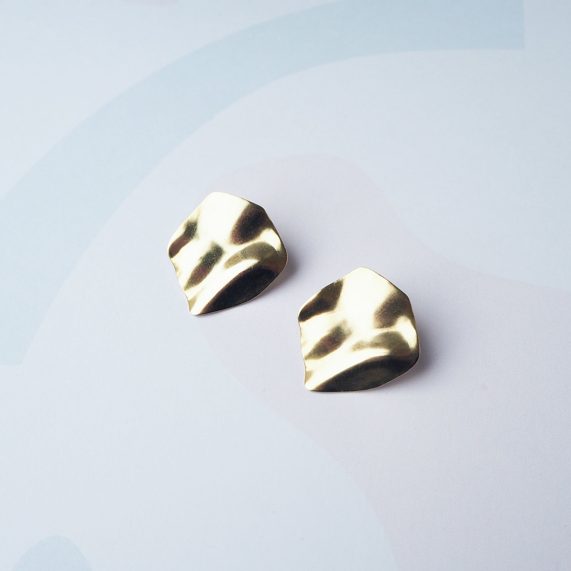 Pair of gold, textured, irregular-shaped earrings.  The earrings have a hammered or crumpled metallic finish.