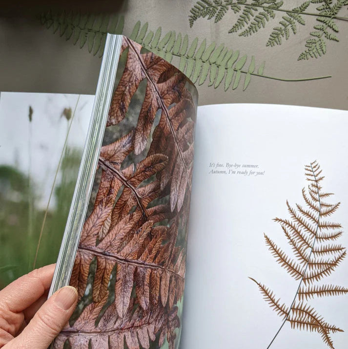 Open book showcasing a close-up photograph of dried brown ferns; text on facing page reads, "It's fine. Bye-bye summer.