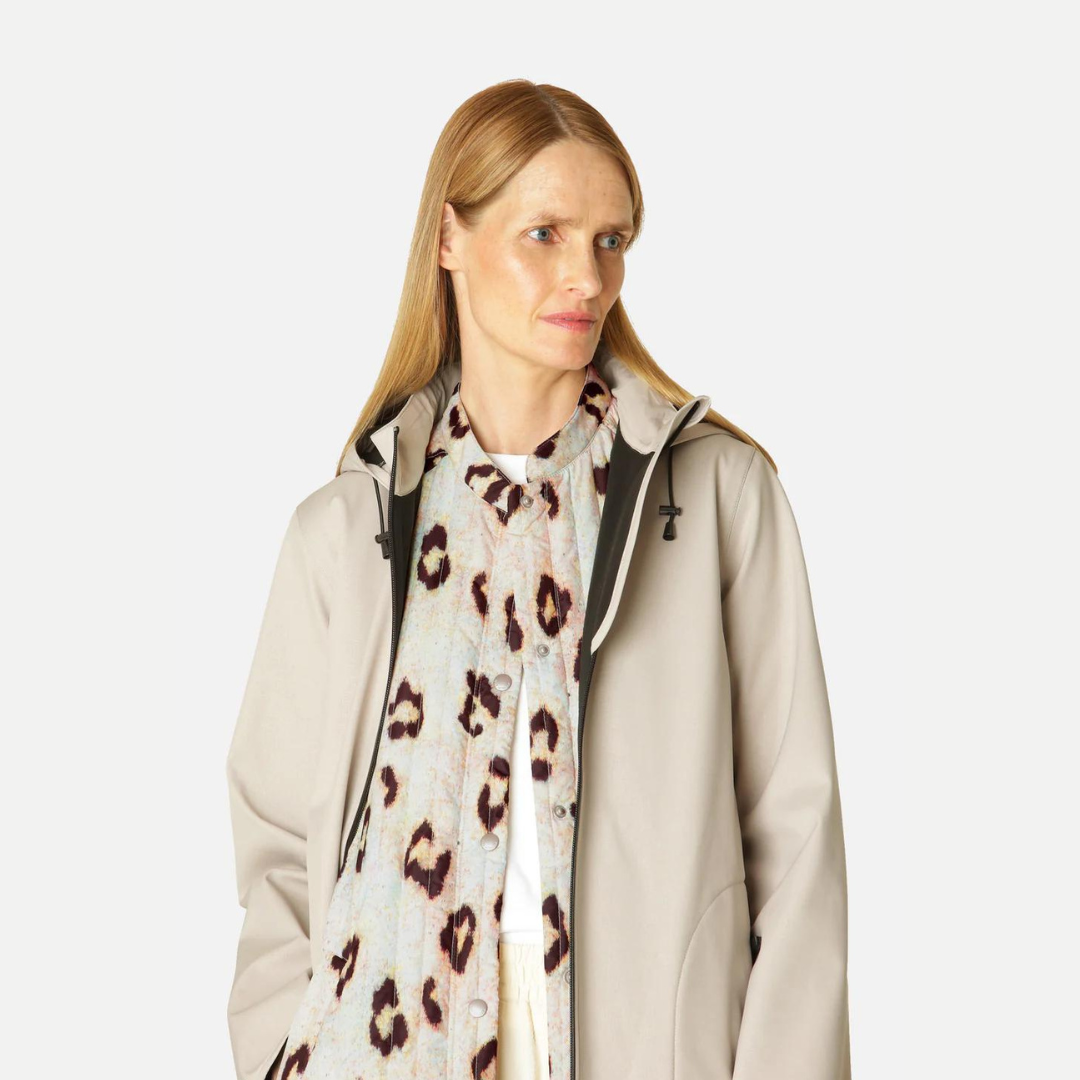 Beige hooded raincoat with a leopard print shirt underneath, worn by a blonde woman.