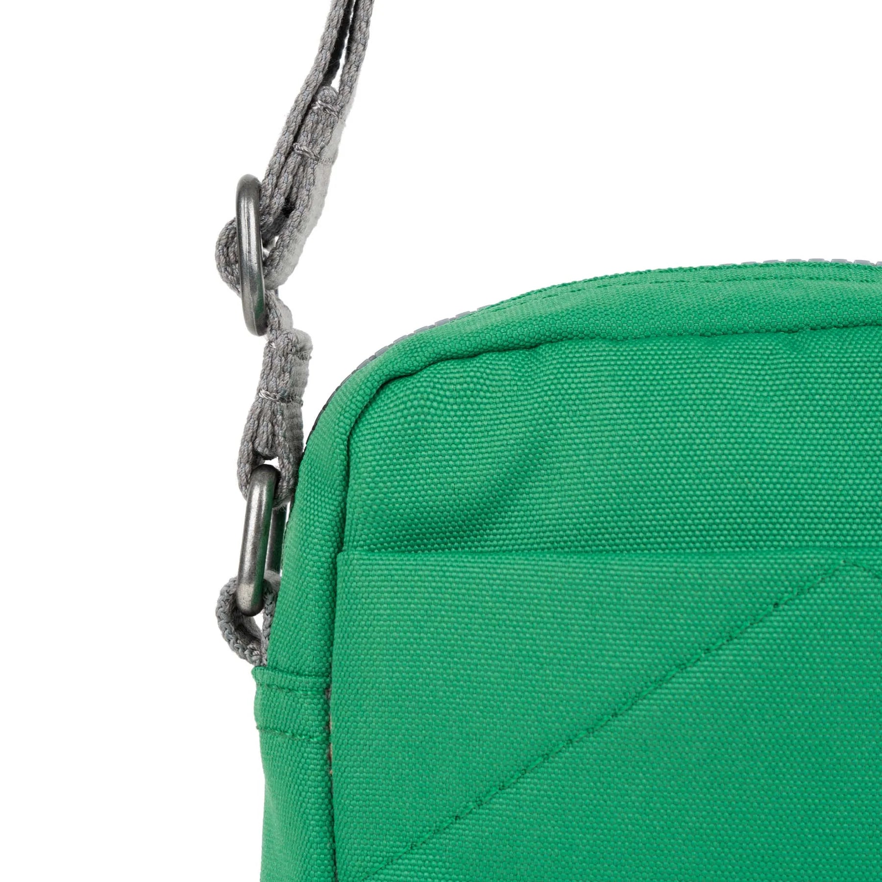 Close-up of a green canvas shoulder bag with gray straps and metallic hardware.