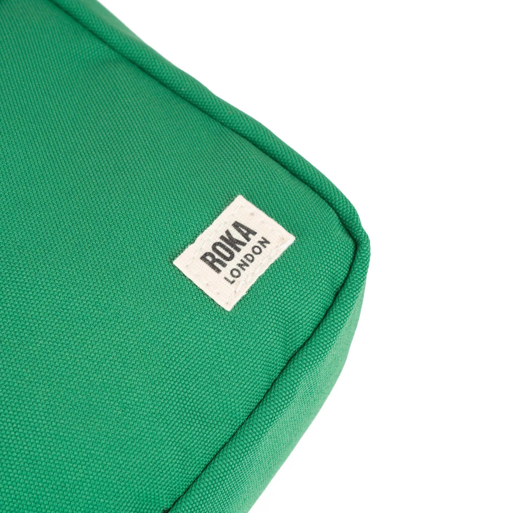 Close-up of a bright green canvas bag with a small "ROKA LONDON" label.
