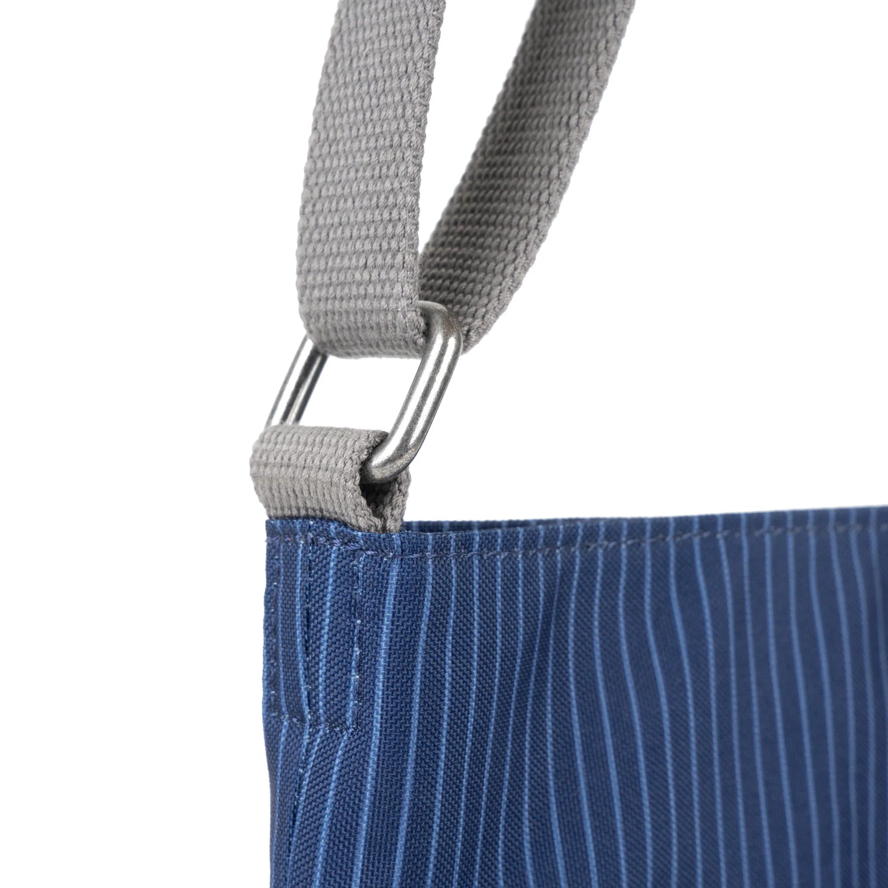 Close-up of a blue striped fabric bag with a gray canvas shoulder strap and silver metal D-ring.