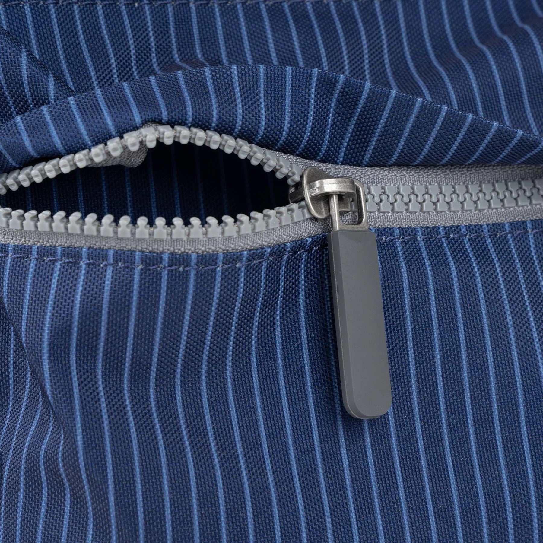 Close-up of a navy blue striped fabric zipper with a gray slider.