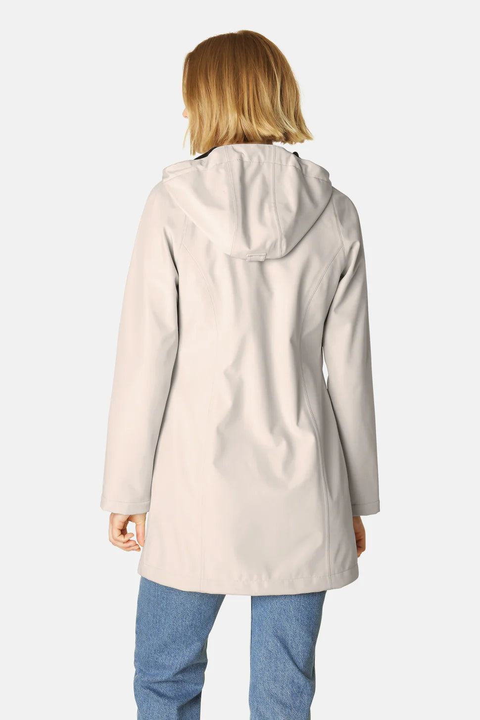 Rear view of a woman wearing a light beige, hooded, waterproof jacket with a smooth texture. The jacket is knee-length and has