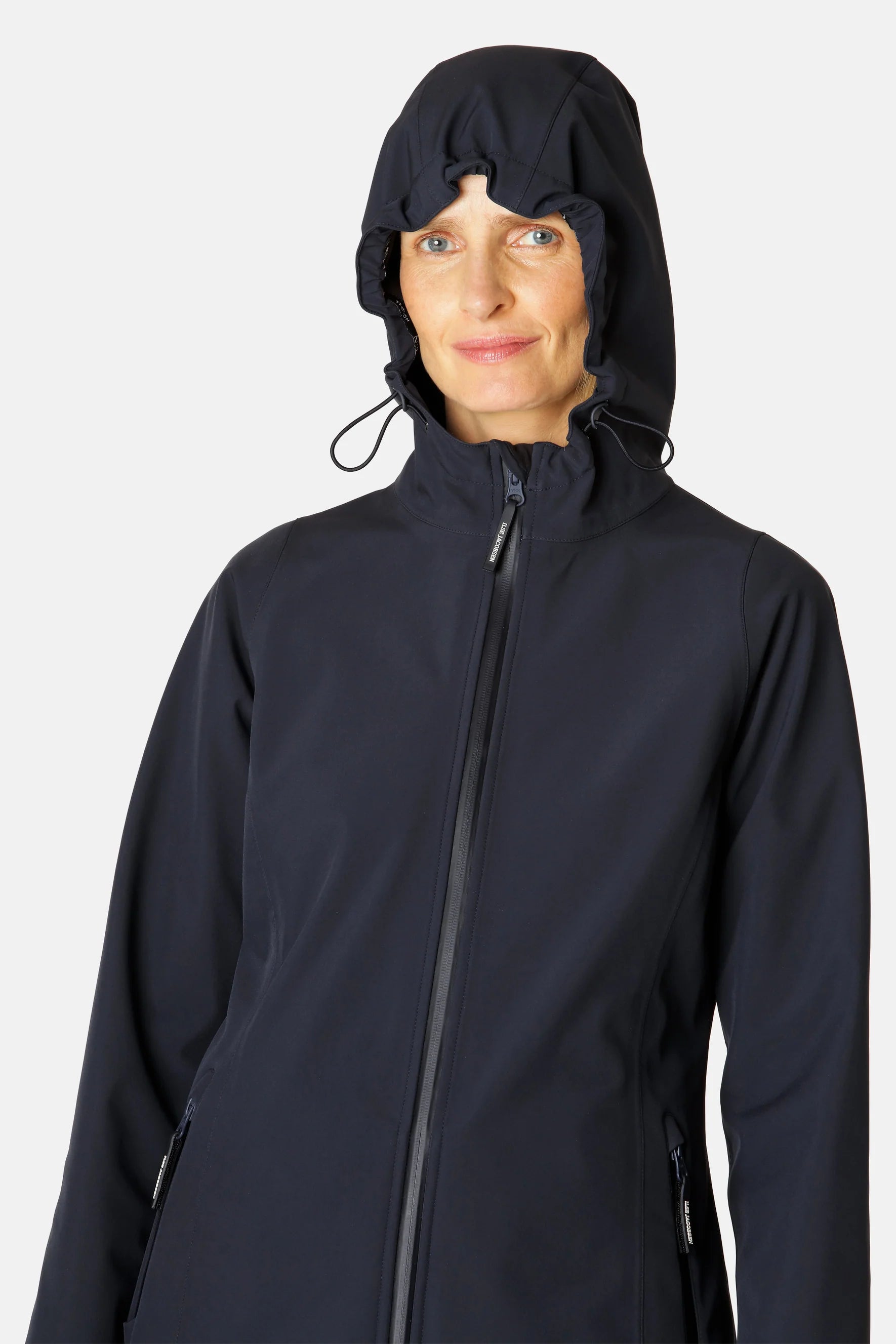 Woman wearing navy blue softshell jacket with a hood, zipped front, and subtle branding. Smooth, matte texture.