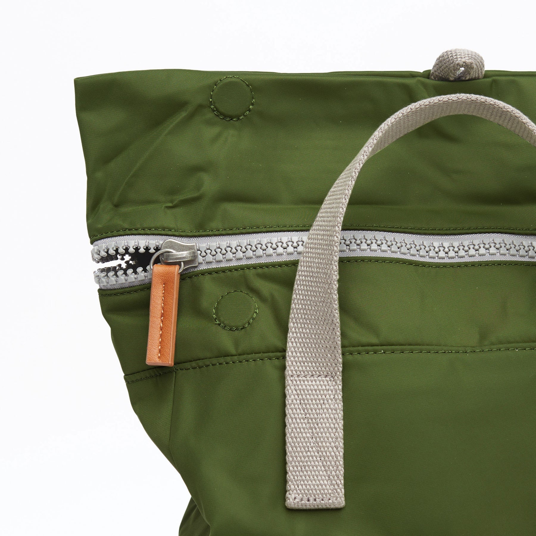 Olive green nylon tote bag with silver zipper, tan leather zipper pull, and light gray fabric handles.