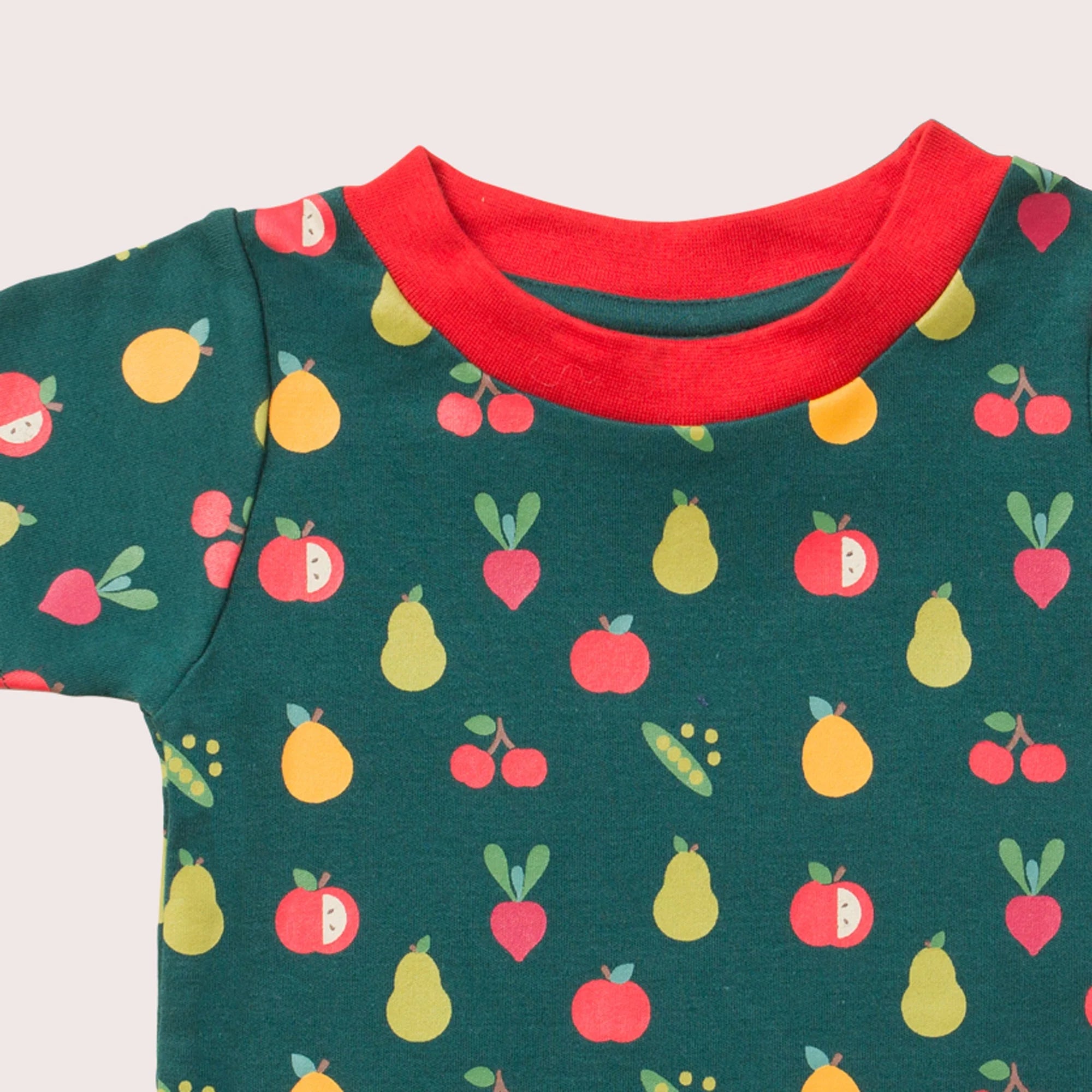 Dark teal children's t-shirt with red neckline, featuring a repeating pattern of apples, pears, cherries, and radishes.
