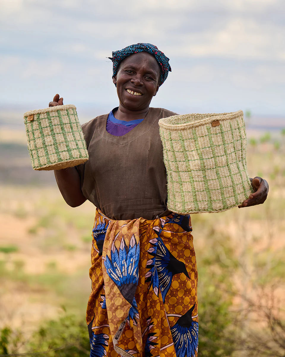 Woman holding two woven baskets; light green and tan with a grid pattern.