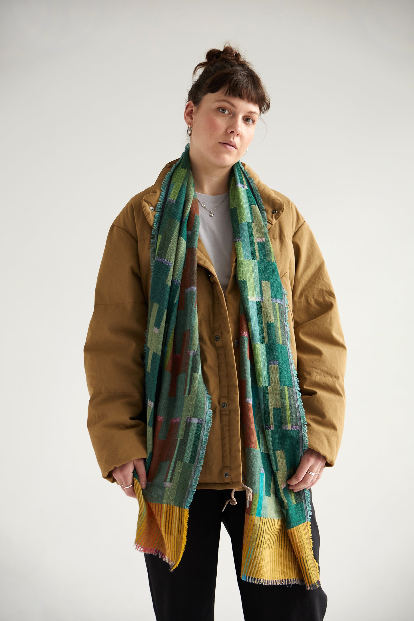A multicolored woven scarf with teal, green, mustard yellow, and rust accents.