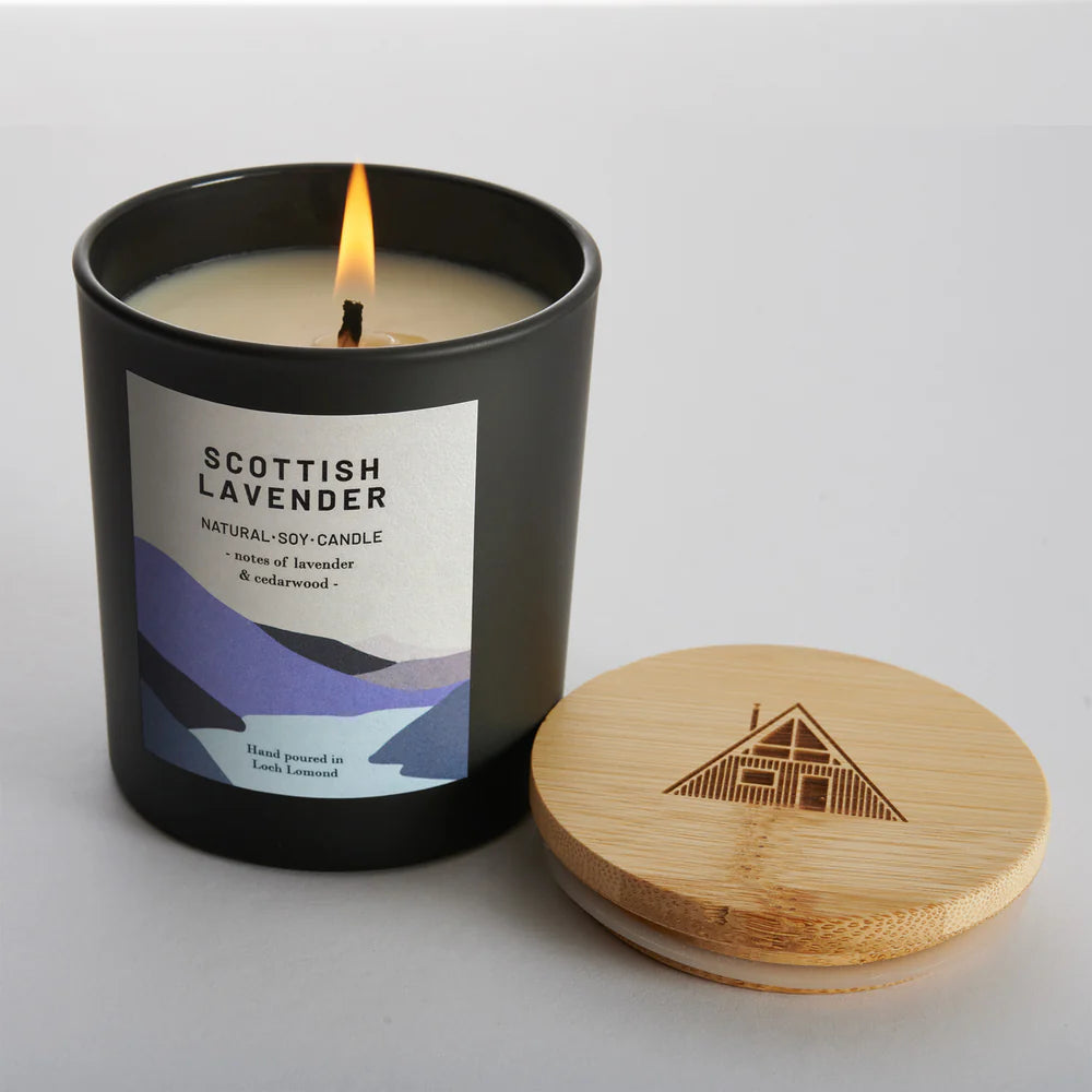 Lit Scottish Lavender soy candle in a black jar with a wooden lid.  The label features lavender and cedarwood notes.