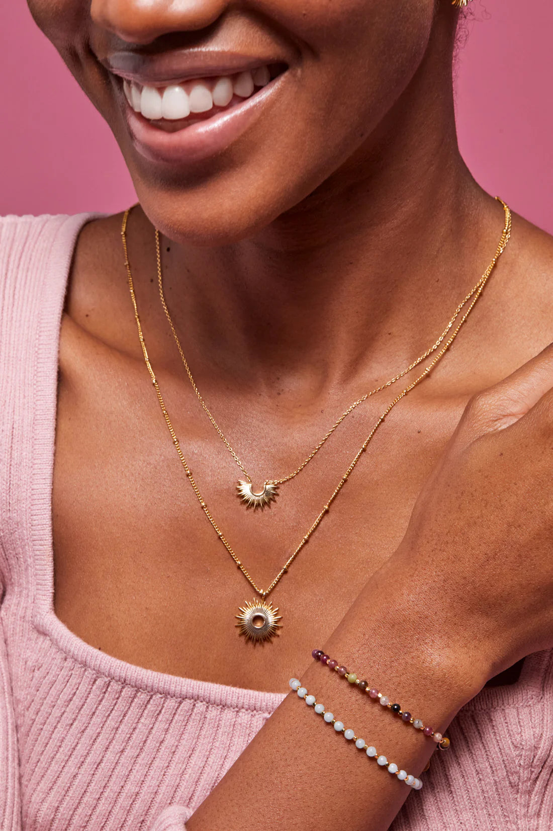 Gold sunburst necklaces and beaded bracelets.  One necklace features a smaller sunburst pendant.
