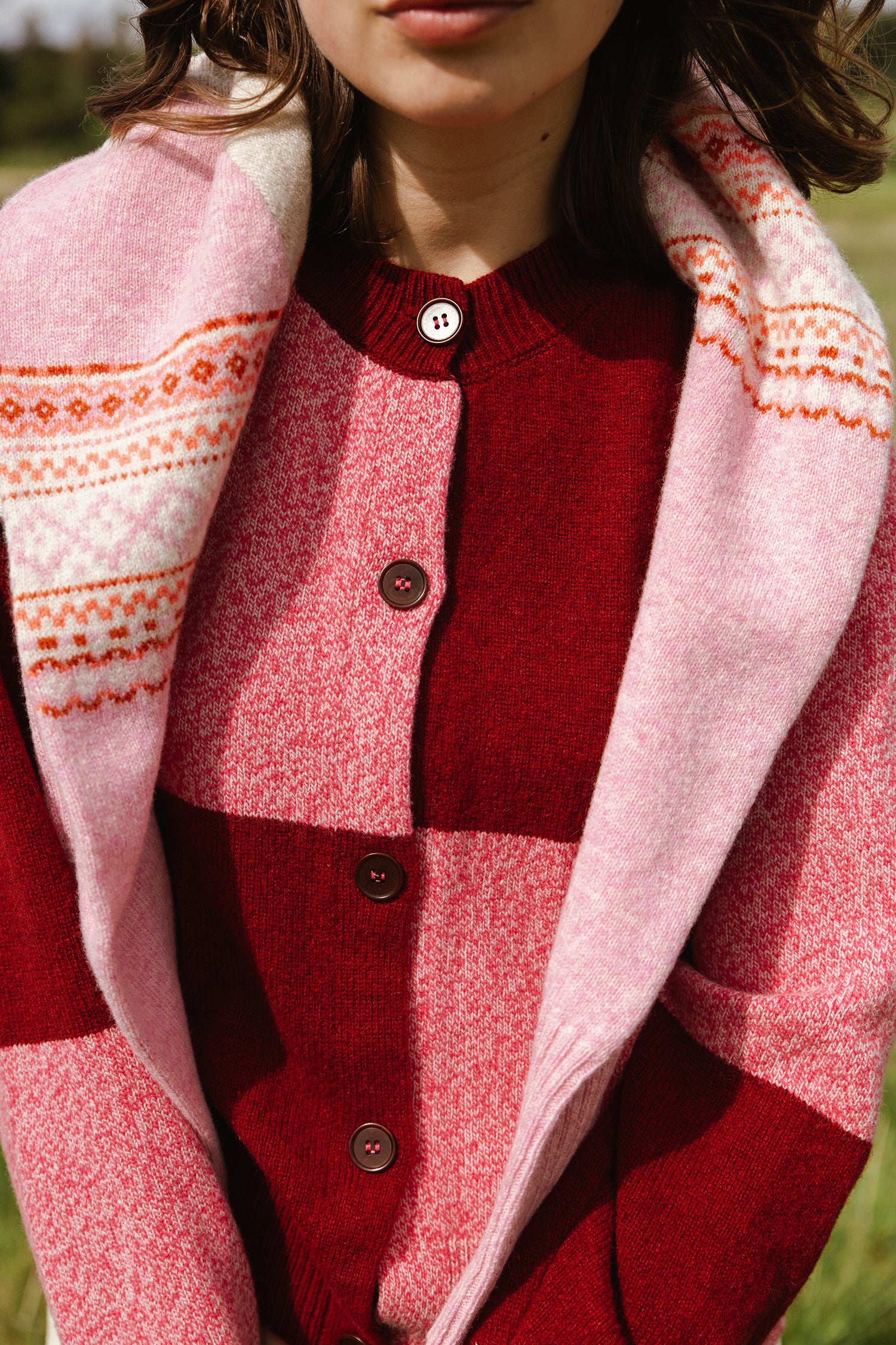 Red and pink color-blocked wool cardigan with a pink patterned scarf draped over the shoulders.