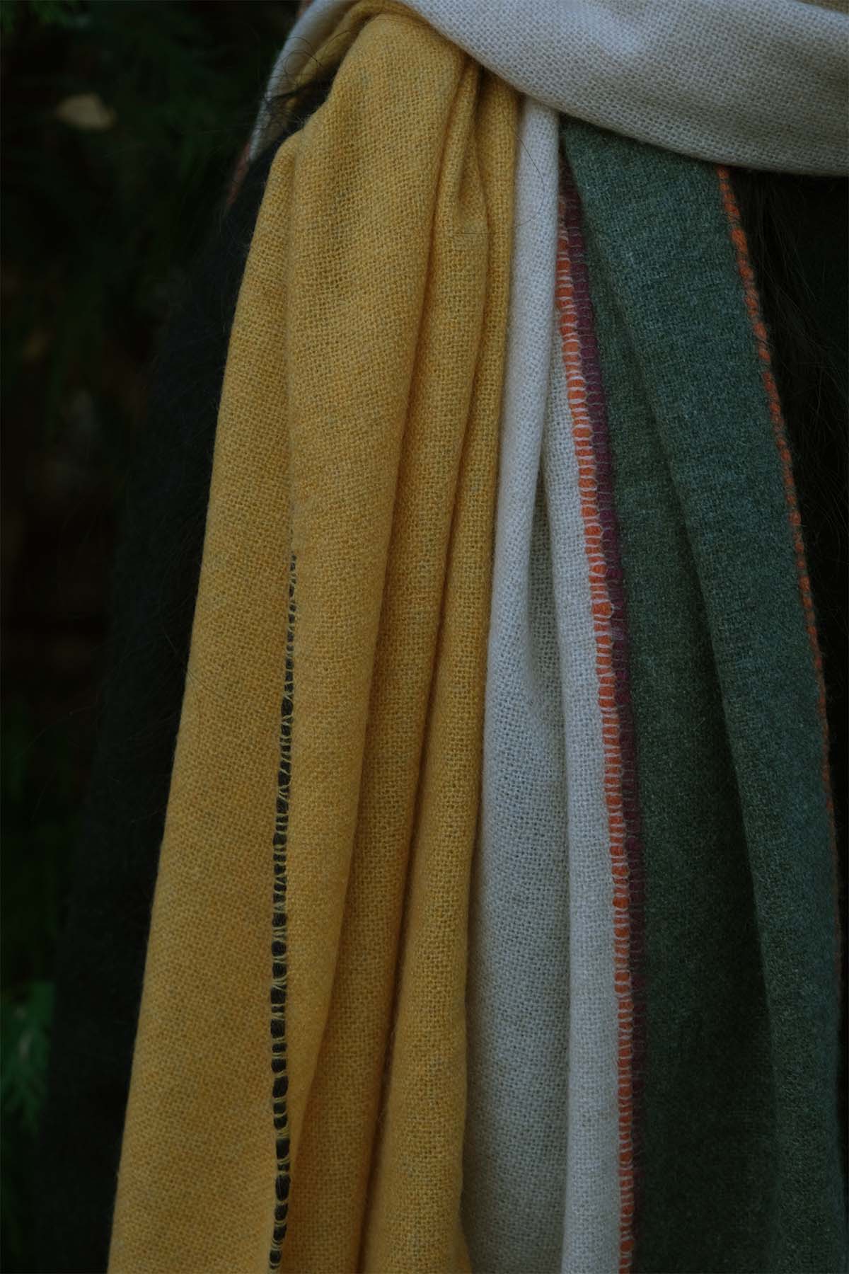 Close-up of a fabric with yellow, green, and white patterns against a dark background
