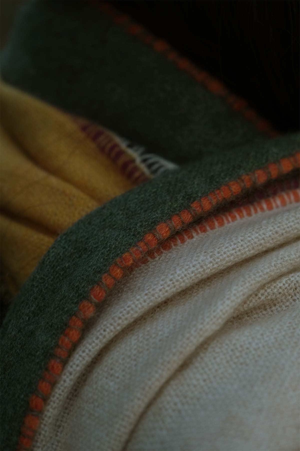 Close-up of fabric with orange stitching on a dark background
