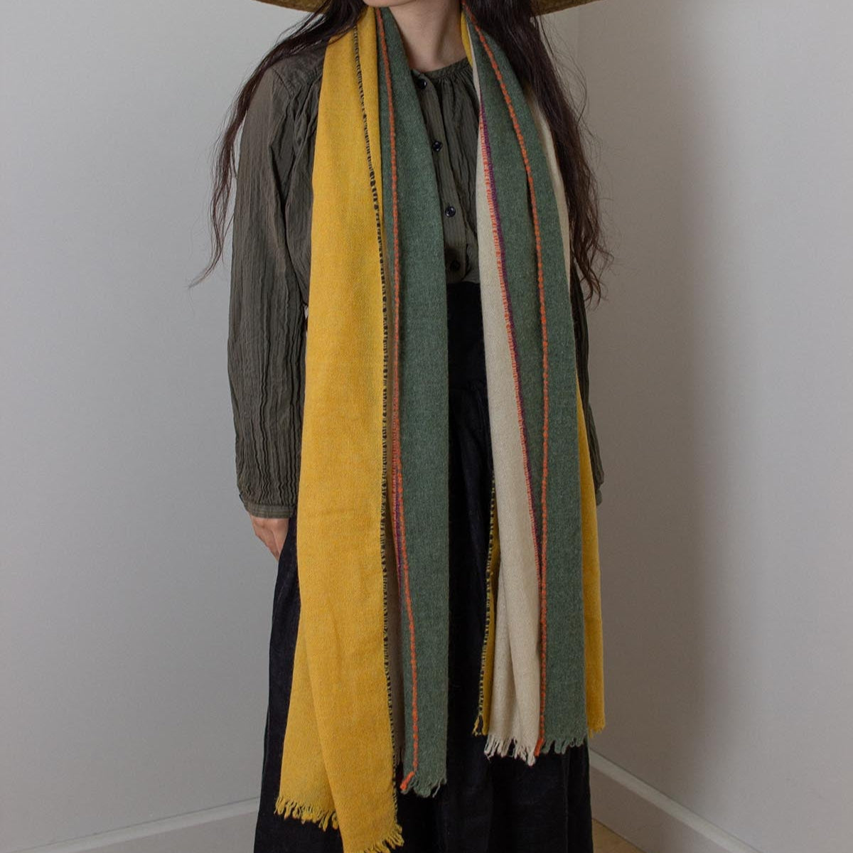 Person wearing a long, multicolored scarf with a plain background