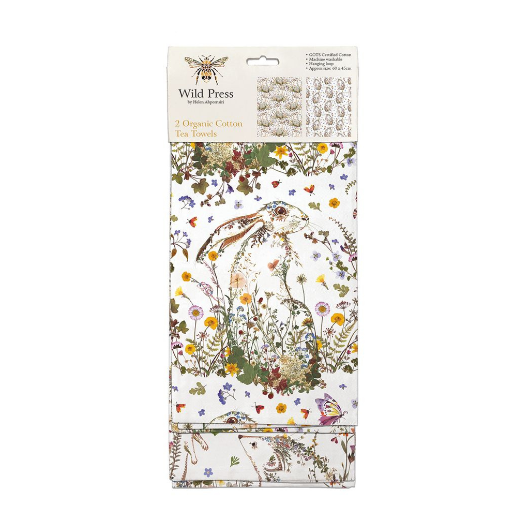 Two organic cotton tea towels; white background with a hare amongst wildflowers and other floral designs.