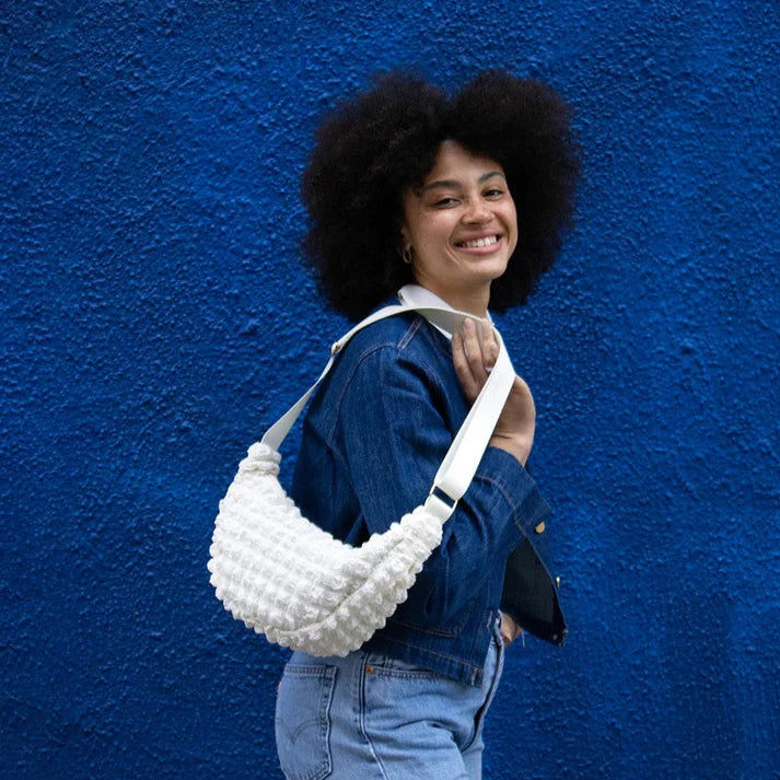White textured crescent-shaped handbag with a long strap.
