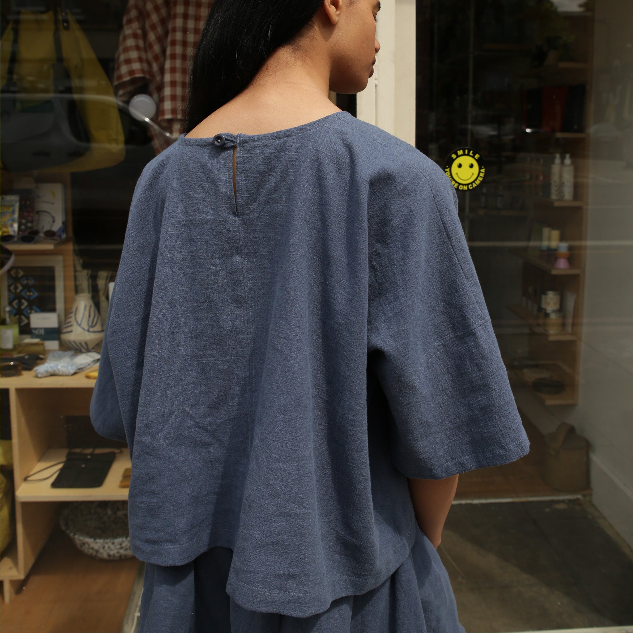 Blue linen top with short sleeves and a keyhole back detail.  The top has a relaxed fit and a slightly tiered hem.